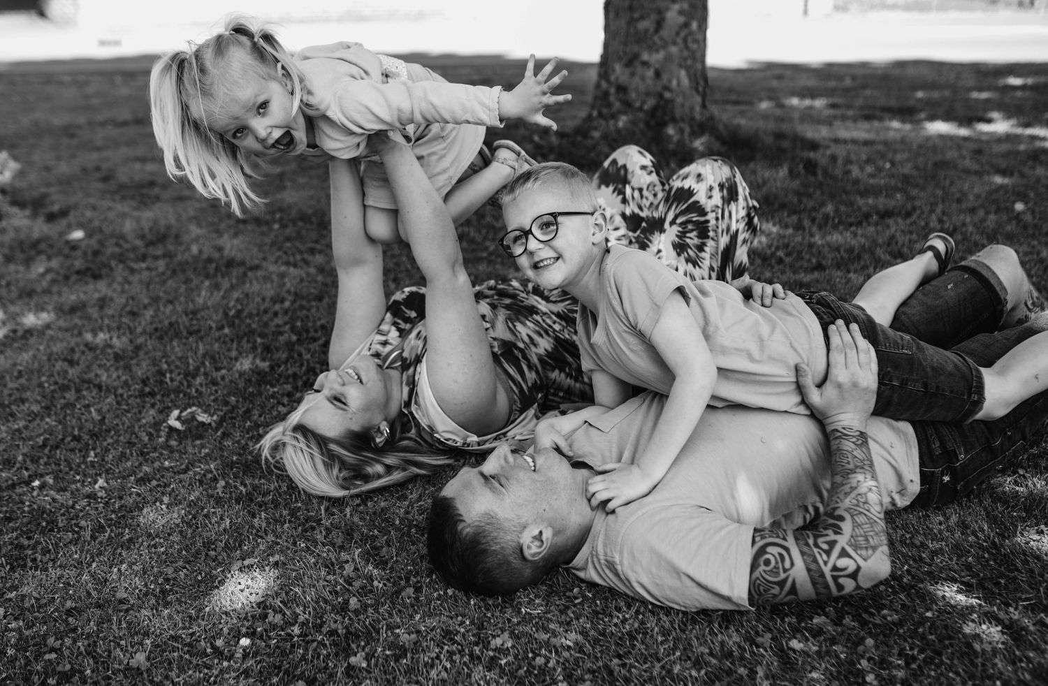 Candid black and white photos of people lying in grass and laughing together.