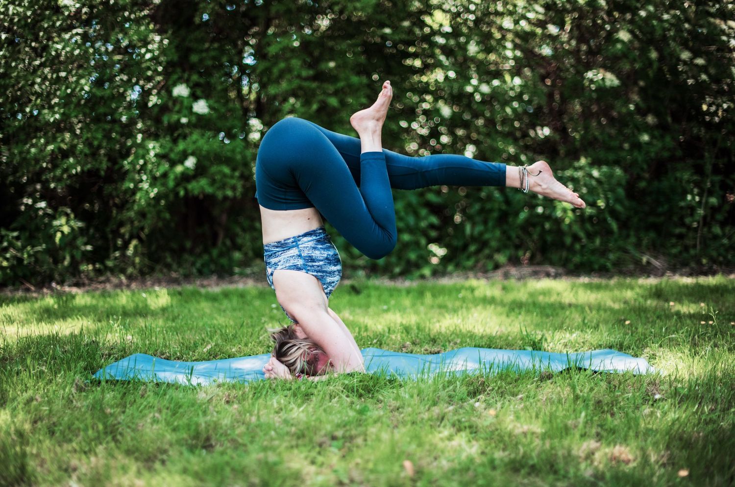 Outdoor yoga practice sequence on blue mat surrounded by greenery.