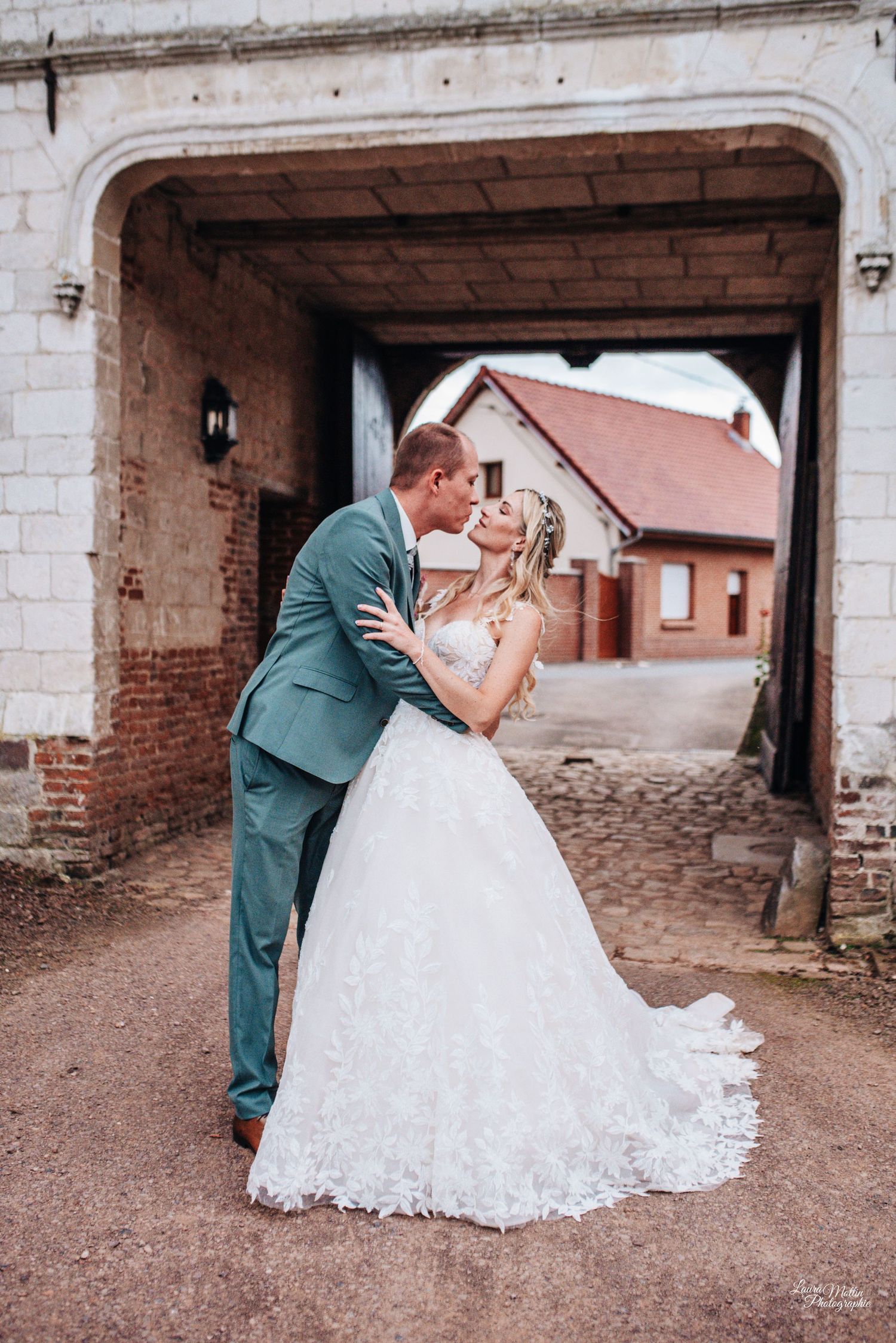 Wedding couple shares romantic moments under stone archway in vintage setting.