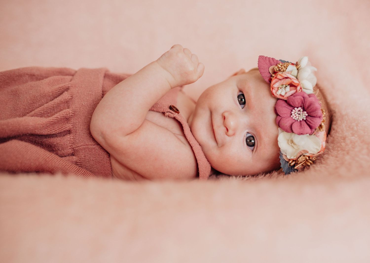 A series of soft pink-toned photos showing a baby with floral accessories.