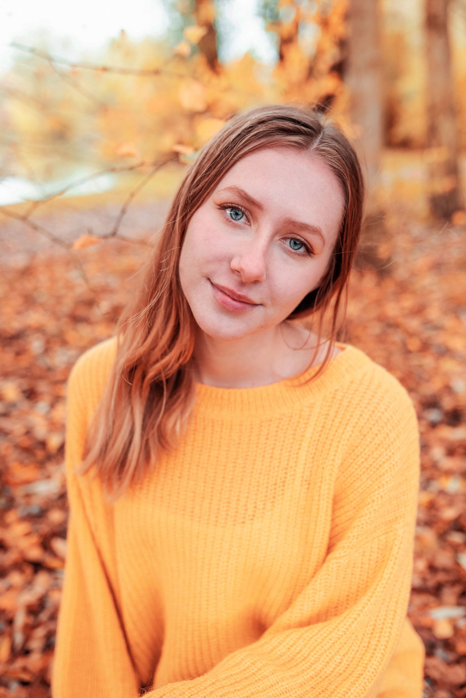 Portrait series in autumn leaves featuring orange sweater against fall foliage.