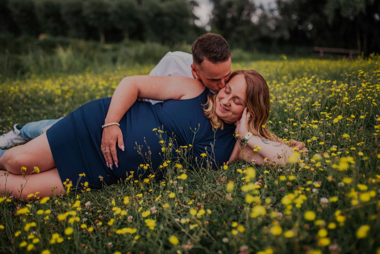 Romantic maternity photos taken in a field of yellow wildflowers.