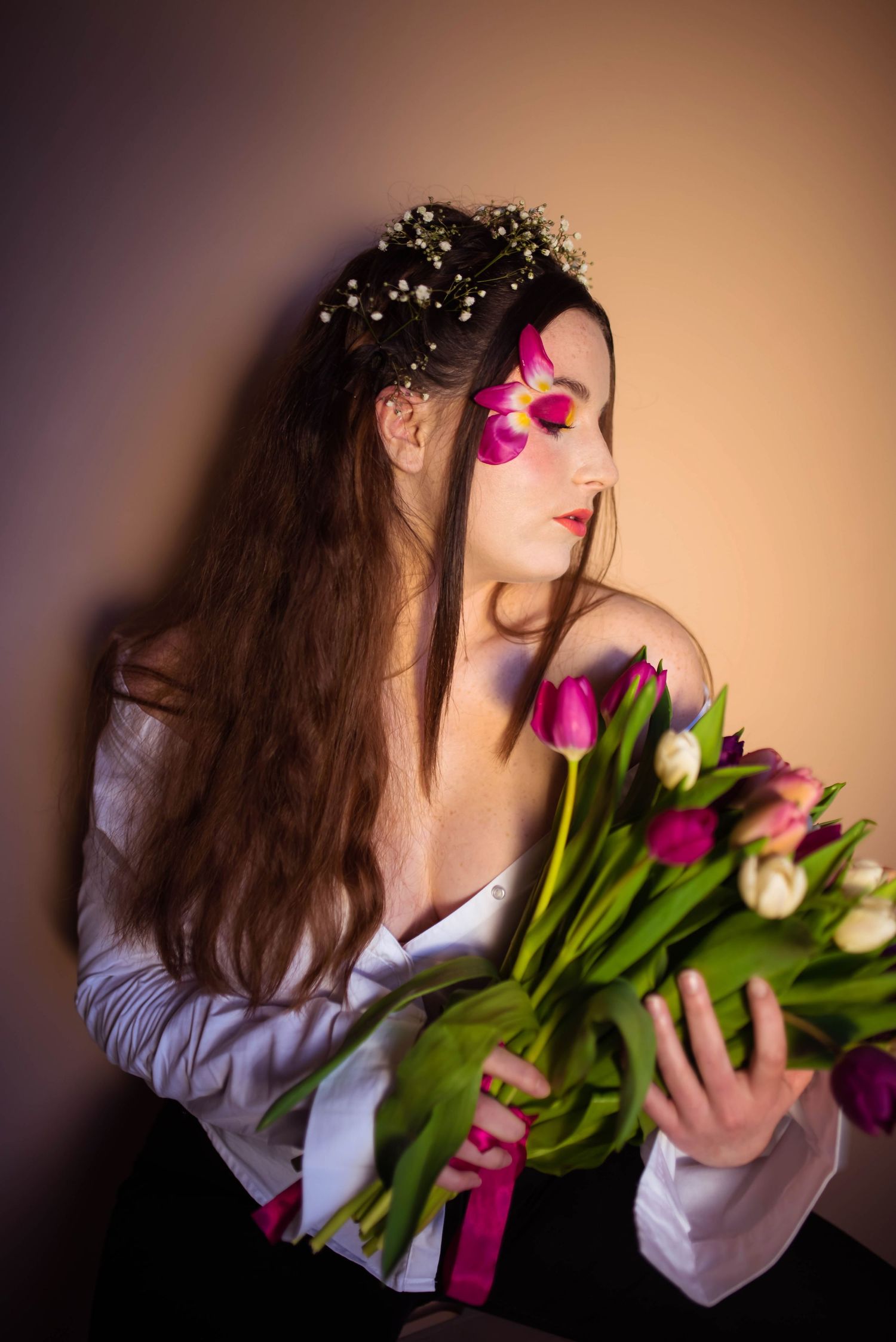Dreamy portrait with tulips and baby's breath crown against warm background.