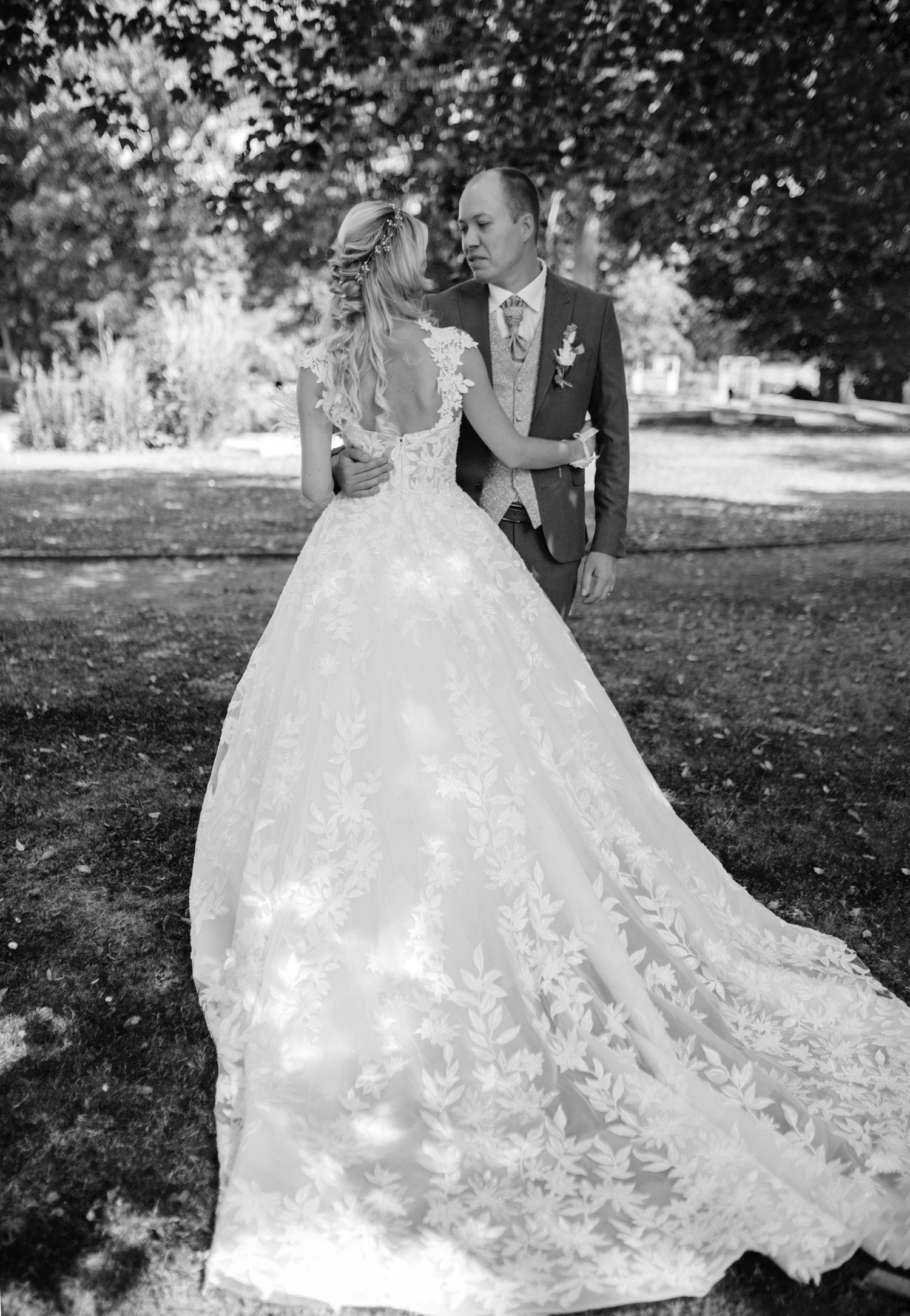 Elegant wedding dress with intricate lace details and flowing train in black and white.