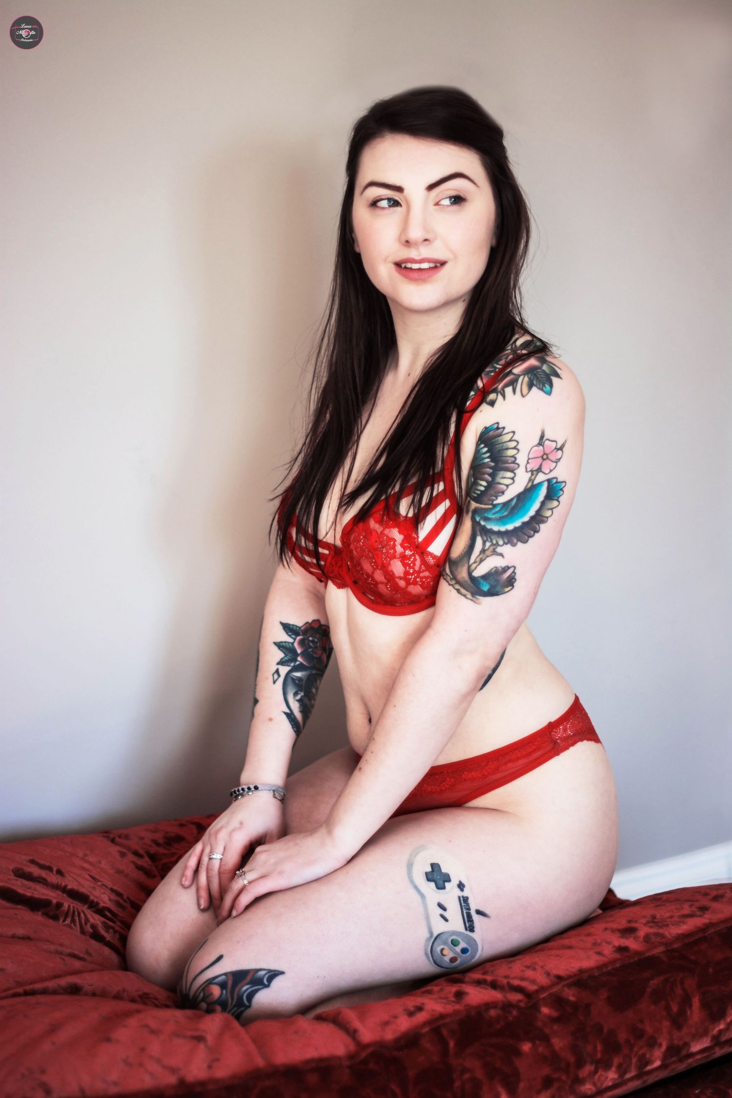 Boudoir photography session featuring red lingerie and visible tattoo art.