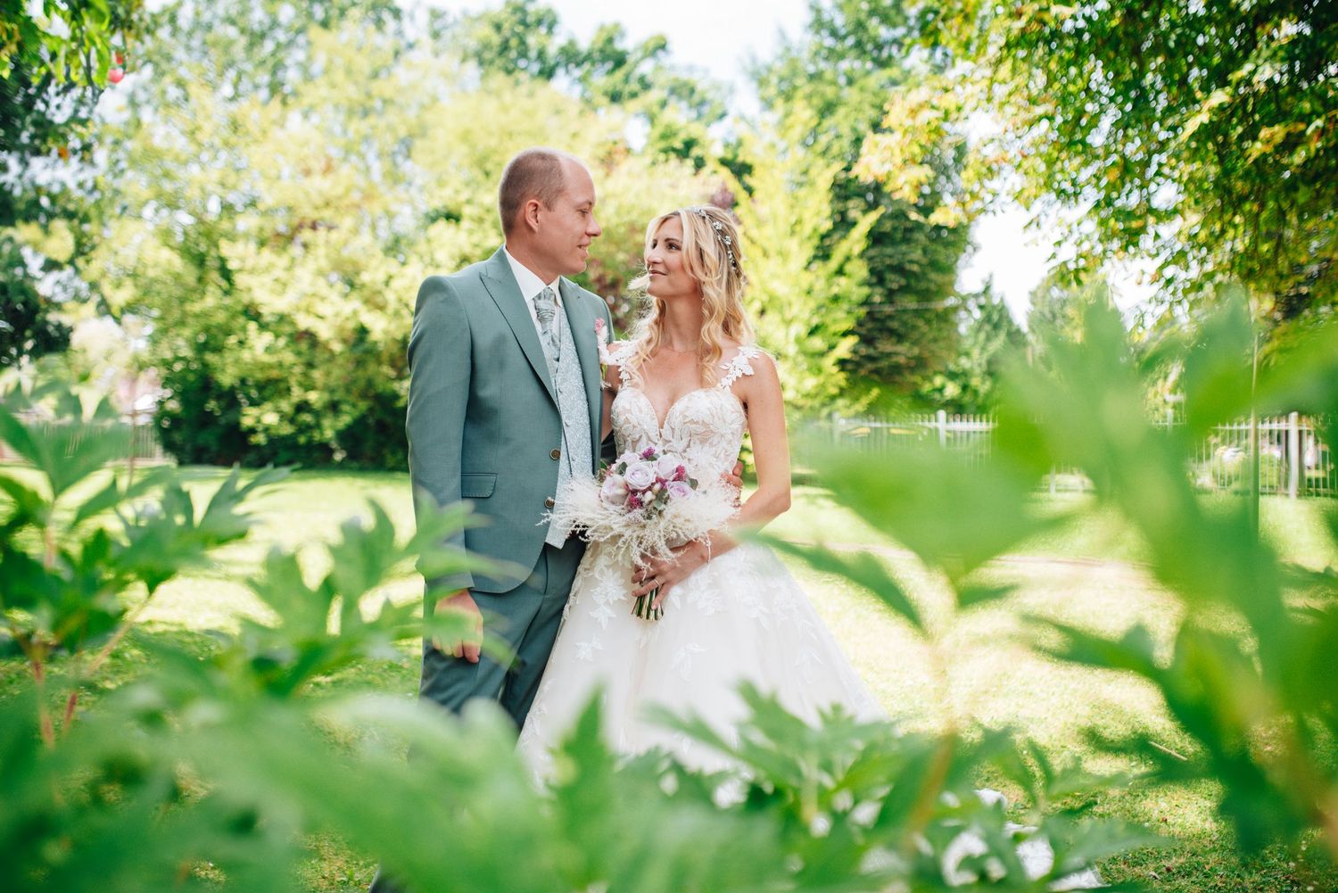 Wedding couple shares intimate moment in lush garden setting.