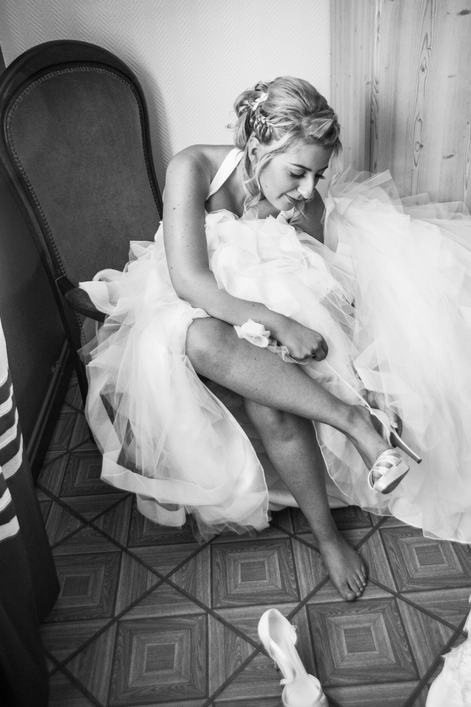 Black and white image shows preparation moment with flowing tulle dress.