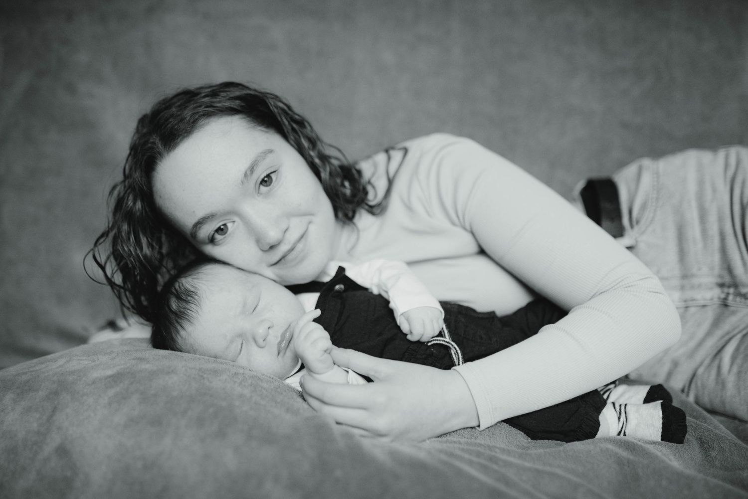 A series of artistic black and white photographs showing a baby lying on soft bedding.