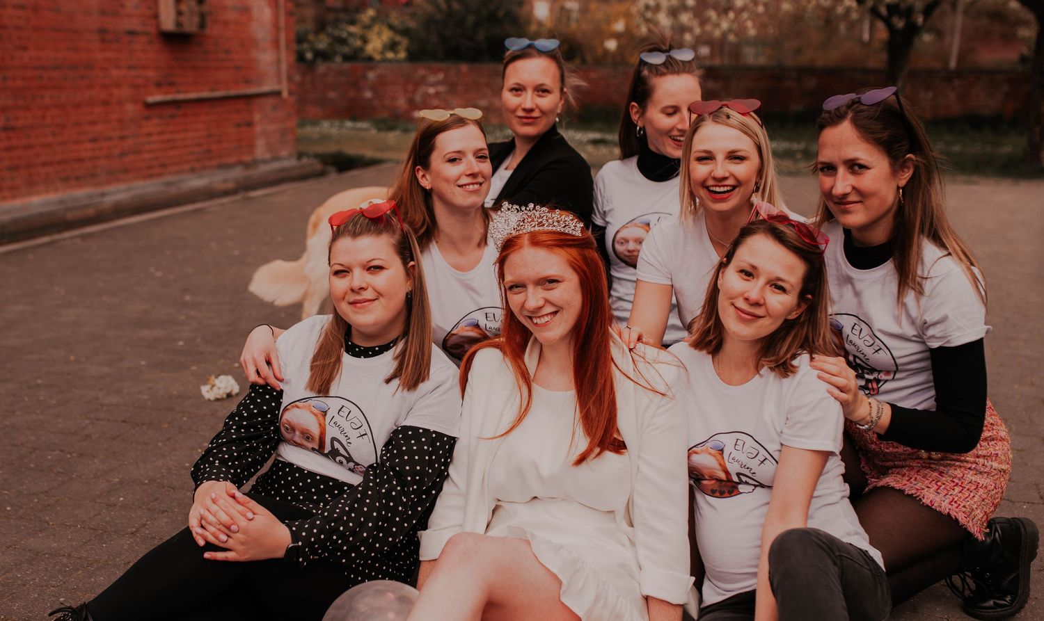 A casual group photo of friends sitting together outdoors near a brick building.