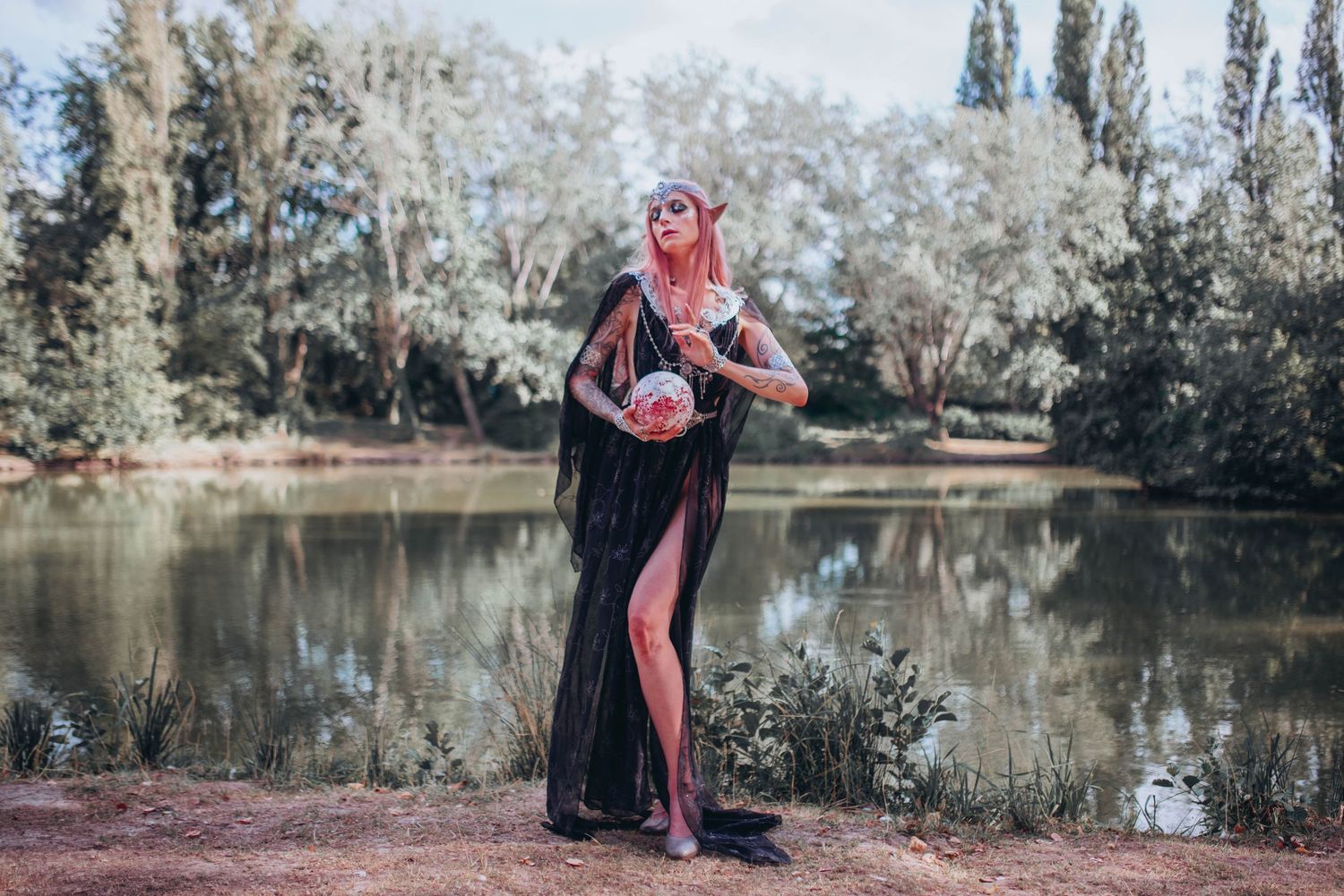 Fantasy-themed photoshoot by a lake with flowing dress and mystical autumn atmosphere.