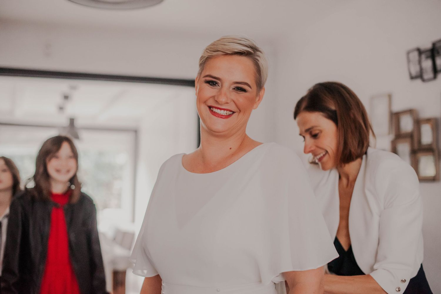 People in white outfits share a candid moment during a wedding celebration.