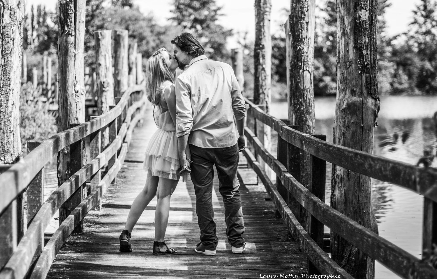 Black and white photos of a couple walking together on a wooden boardwalk through a scenic nature area.