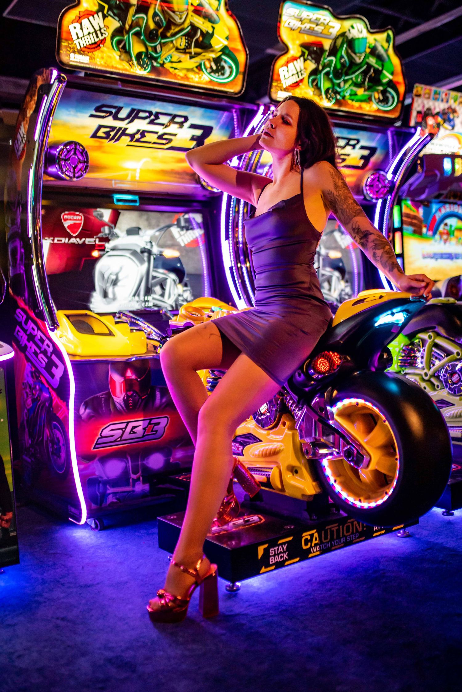 Neon-lit arcade gaming setup with motorcycle simulators and colorful lighting effects.