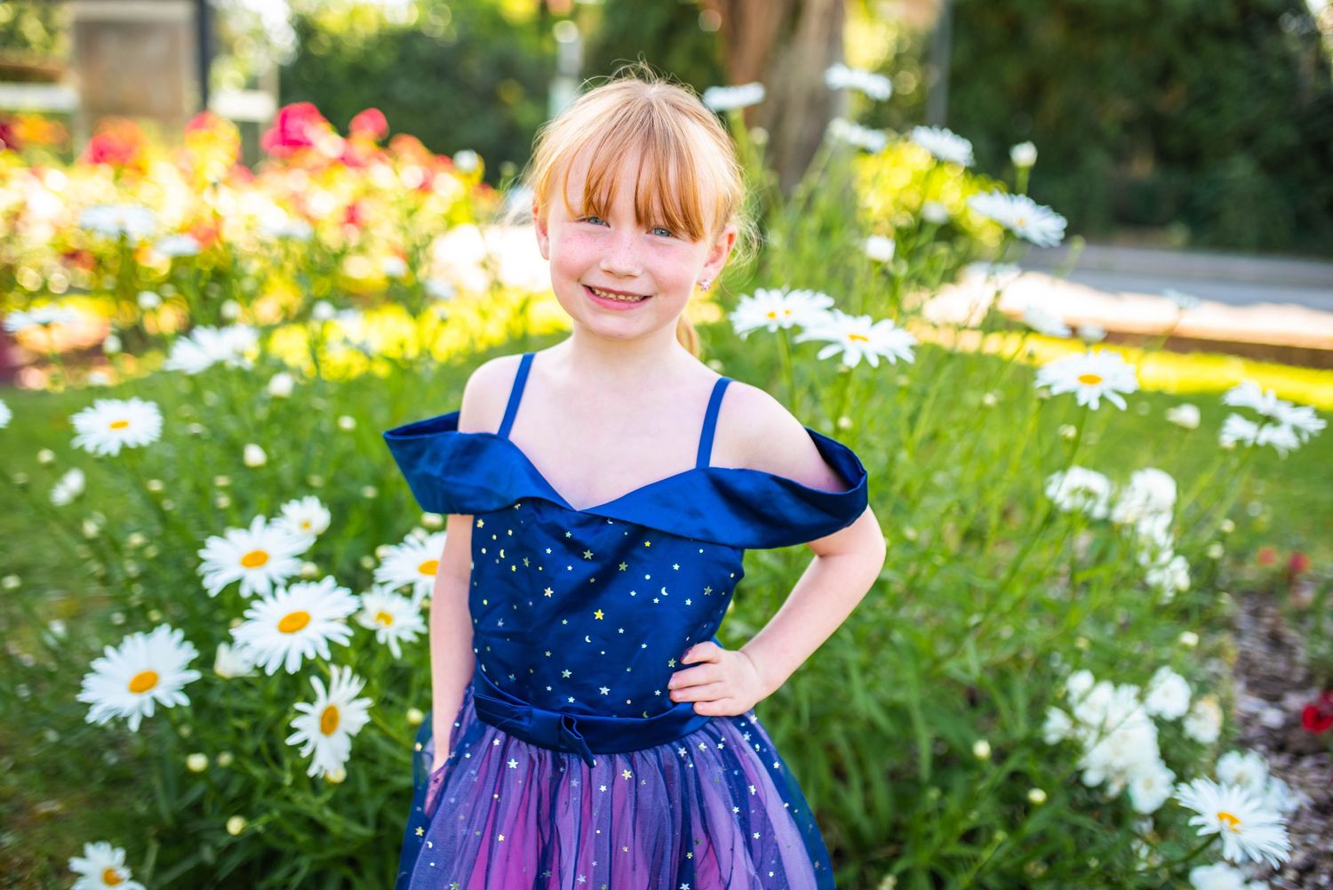 Children playing in a garden with blooming daisies and colorful dresses.