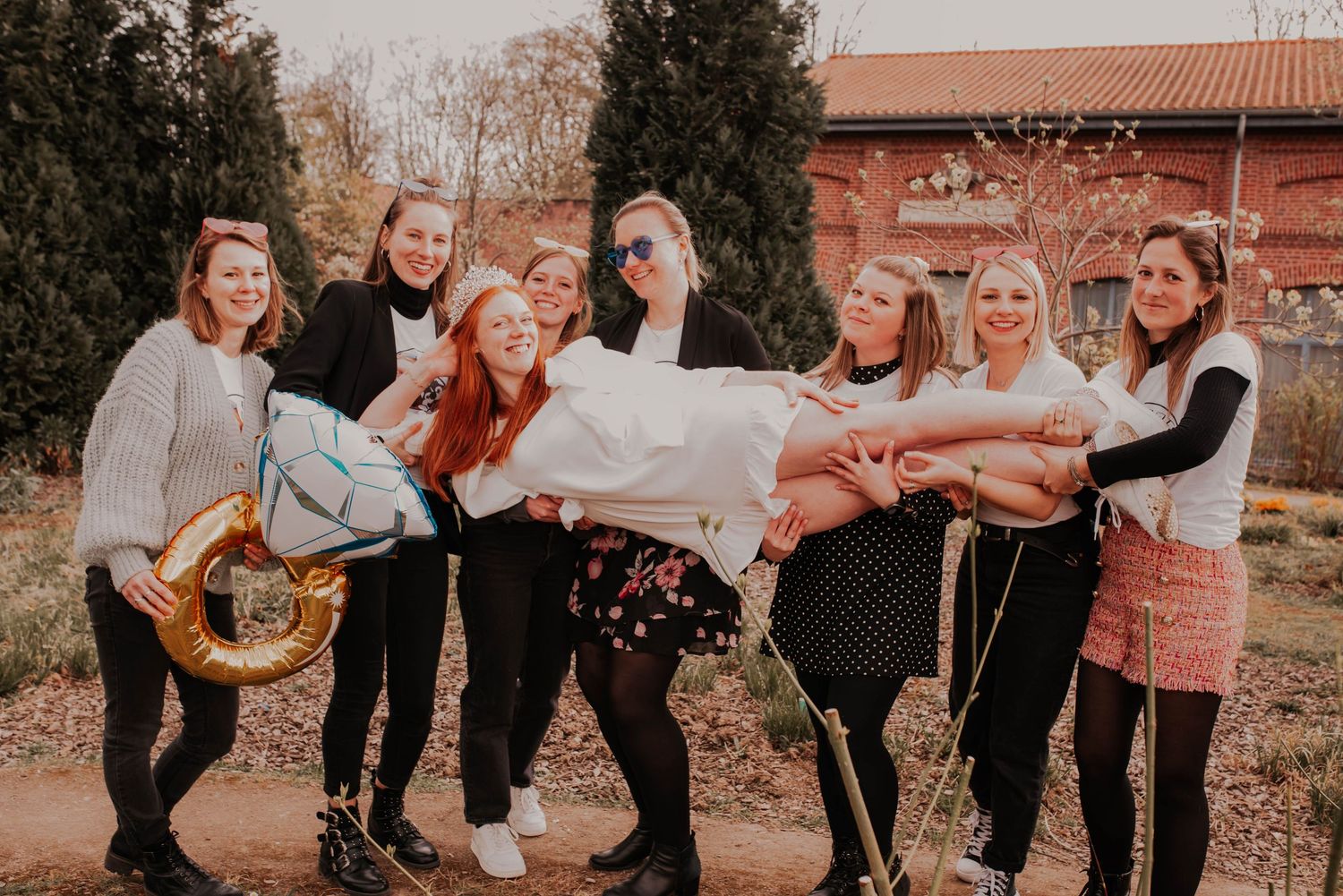 Friends having fun during a photoshoot, pretending to carry someone horizontally.