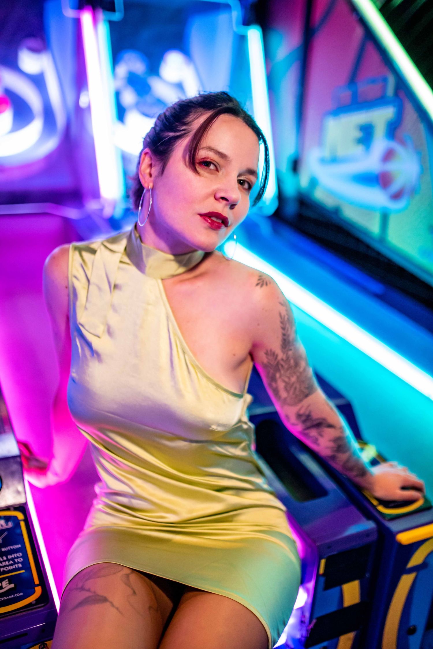 Arcade gaming room photoshoot with vibrant neon lights and vintage aesthetic.