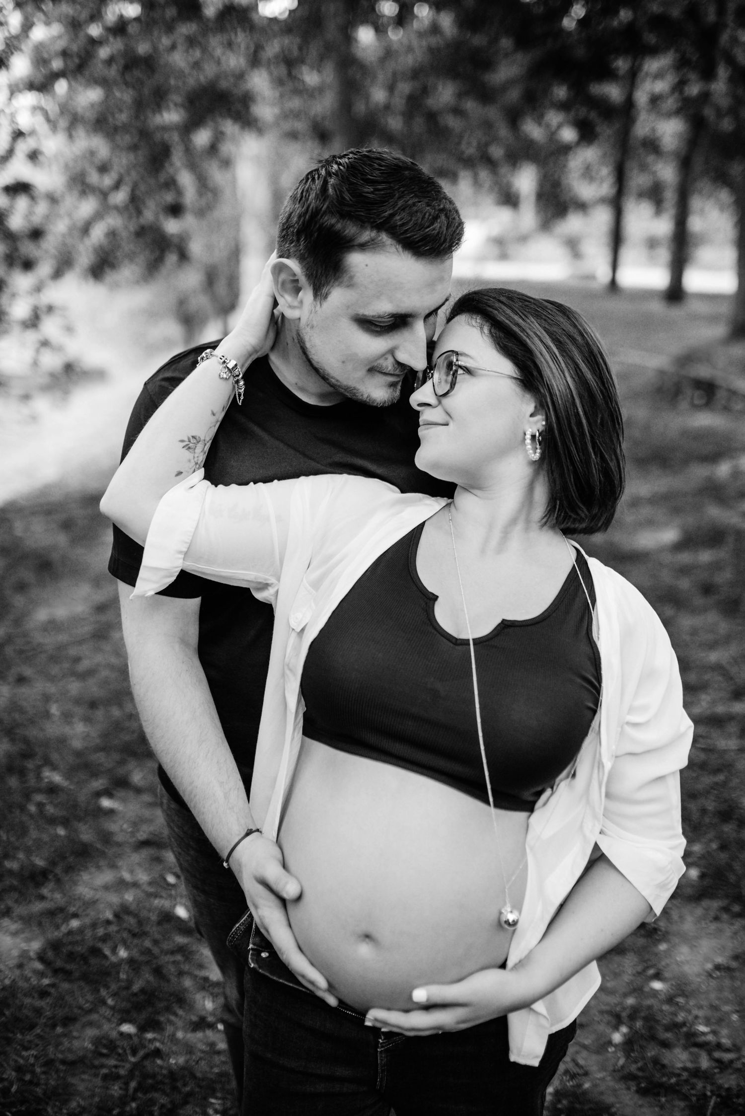 Intimate black and white maternity photos showing couple's connection in natural setting.
