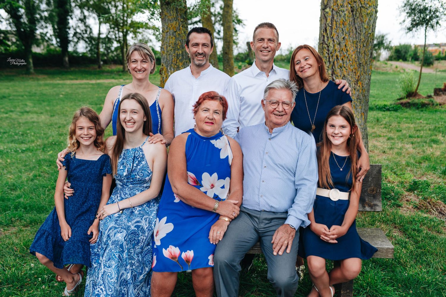 Family portrait session outdoors with coordinated blue and white outfits on a sunny day.