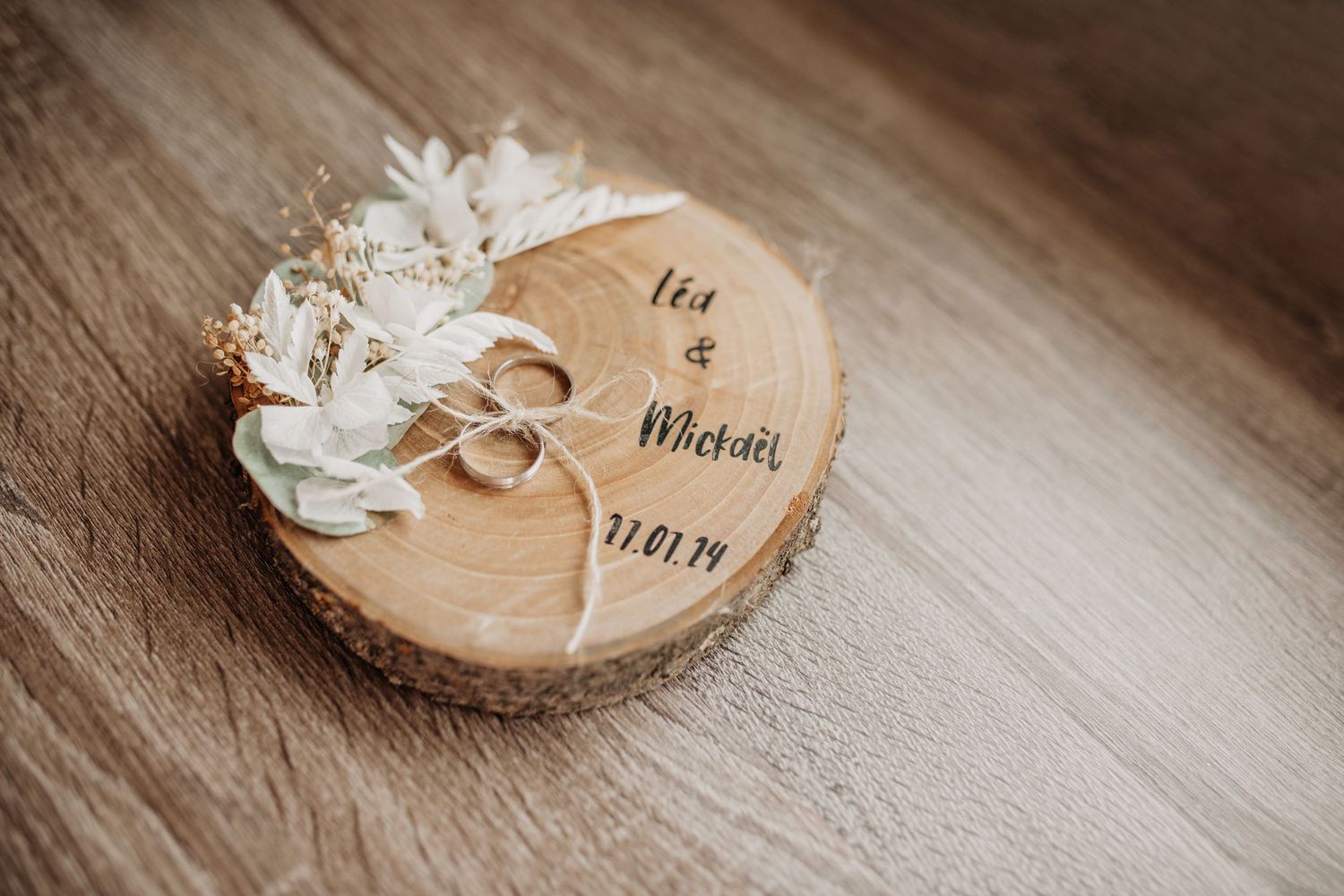 Wooden log slice wedding ring holders with white flowers and name cards.