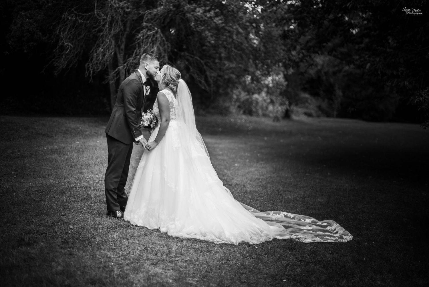 Black and white wedding portrait captured in a serene garden setting.