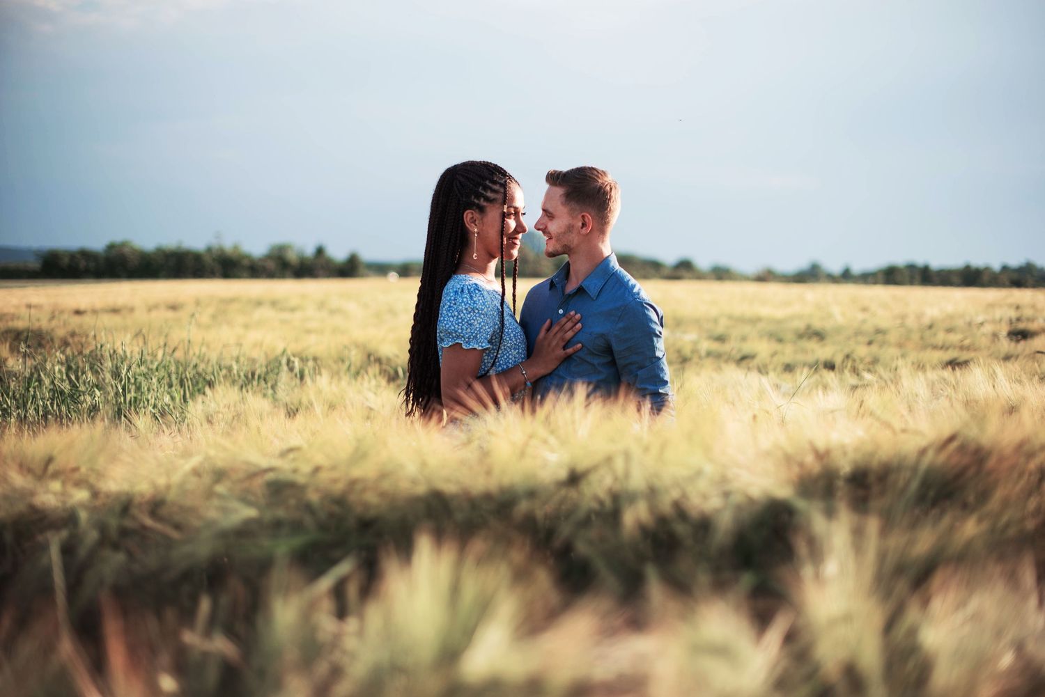 Romantic couple photographed in golden wheat field during sunset.