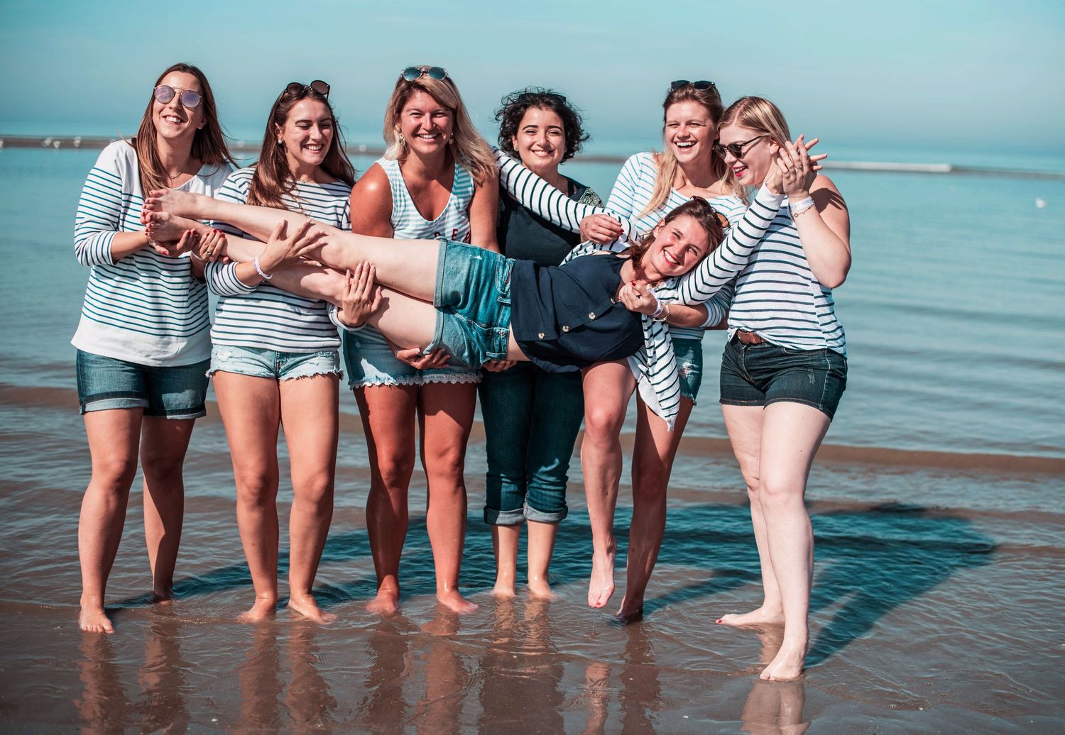 Group of friends having fun at the beach with feet in water.