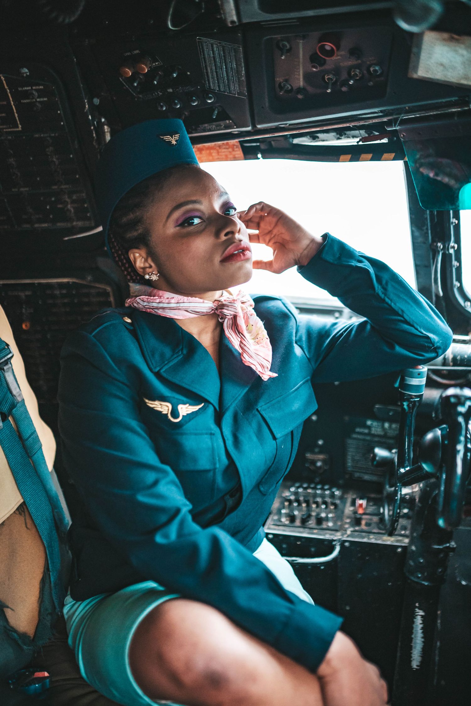 Pilot in uniform working controls inside commercial airplane cockpit.