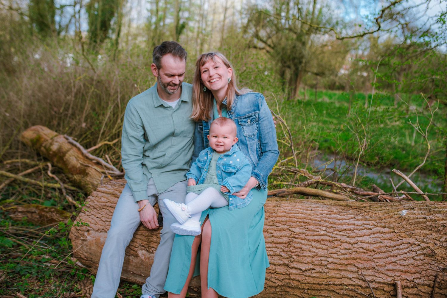 Family portrait session in a natural outdoor setting with trees and fallen logs.