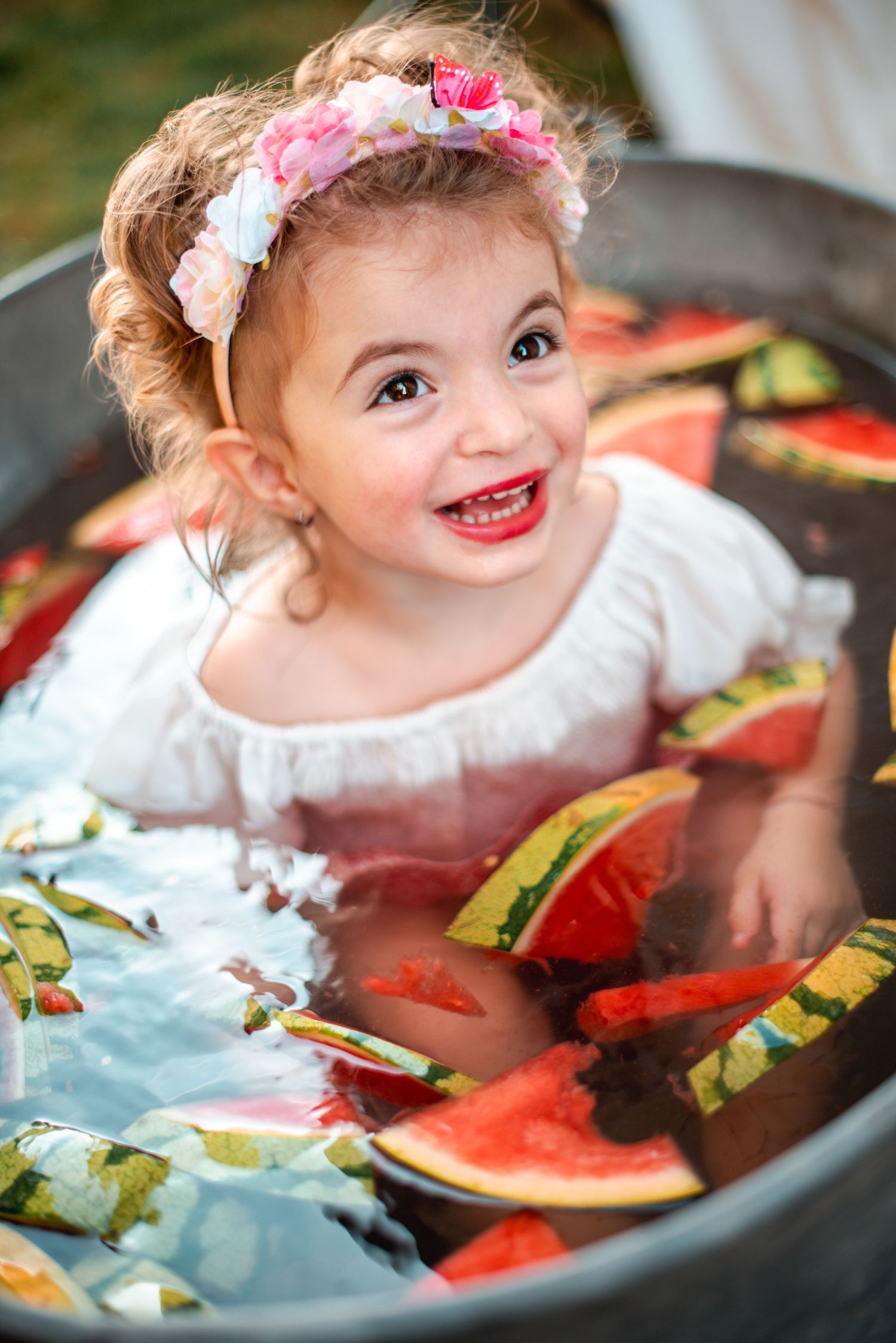 A series of photos showing a small child in white clothing enjoying watermelon slices at a table.