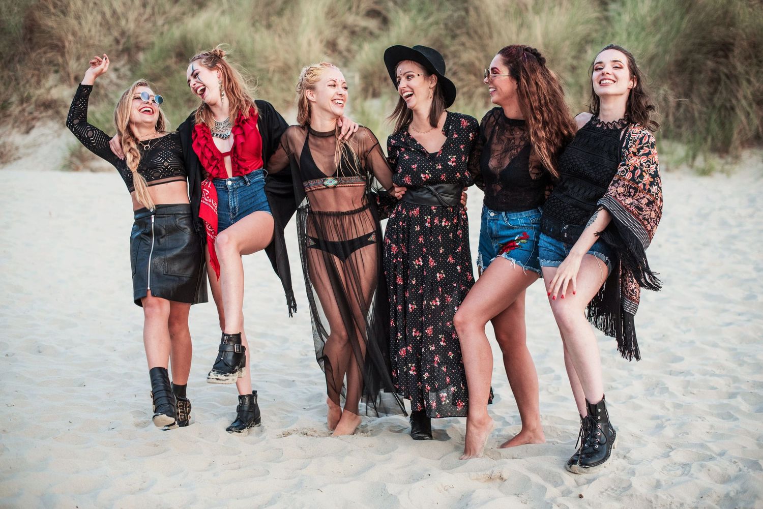 Group of friends walking along the beach showing their legs and boots.