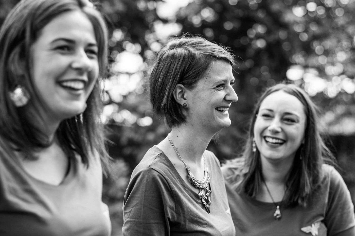 Candid black and white photo of friends laughing together in natural lighting.