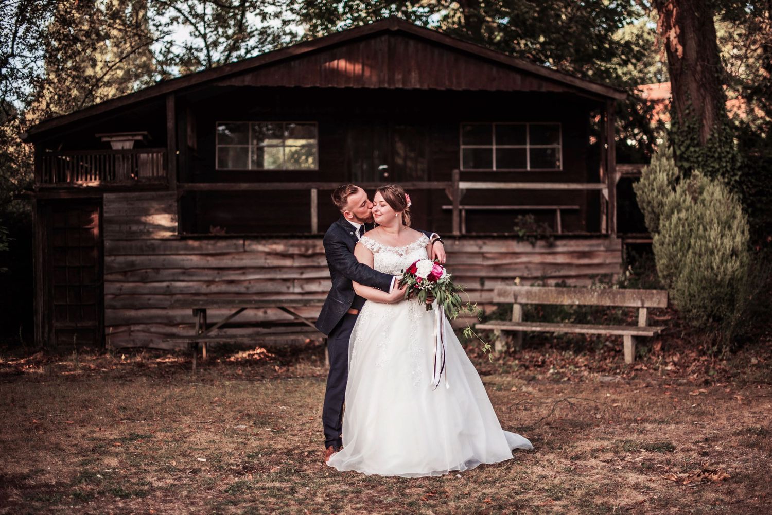 Rustic wooden cabin provides backdrop for outdoor wedding portraits.