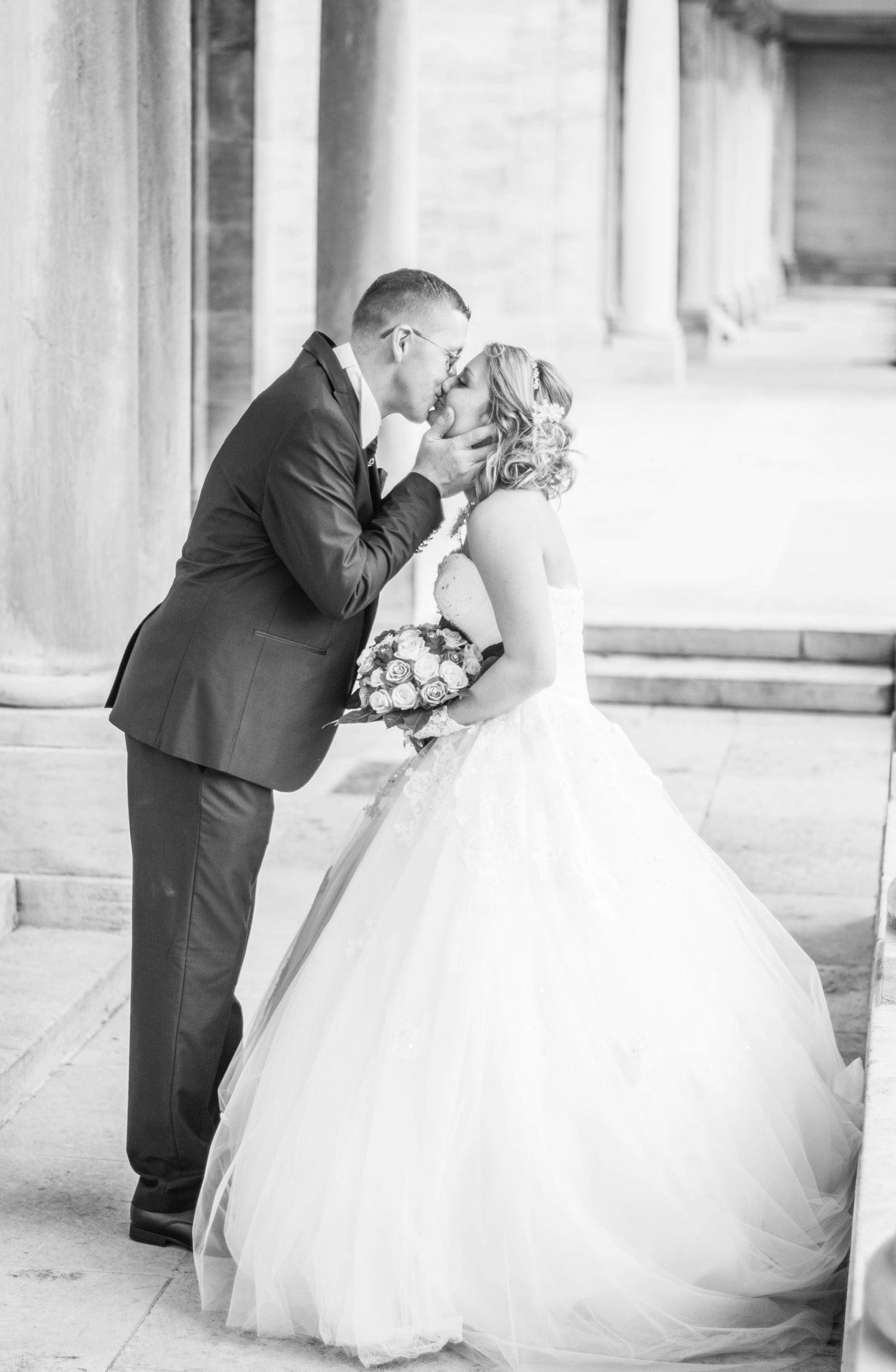 Elegant black and white wedding photos showing romantic moments in a columned venue.