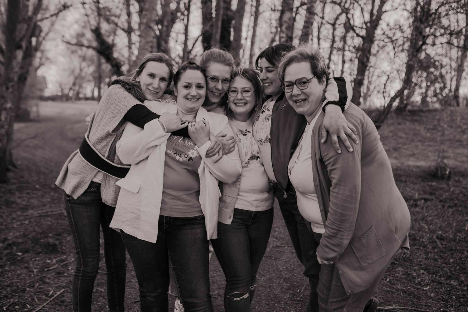 Group laughing together in casual attire during a black and white outdoor photoshoot.