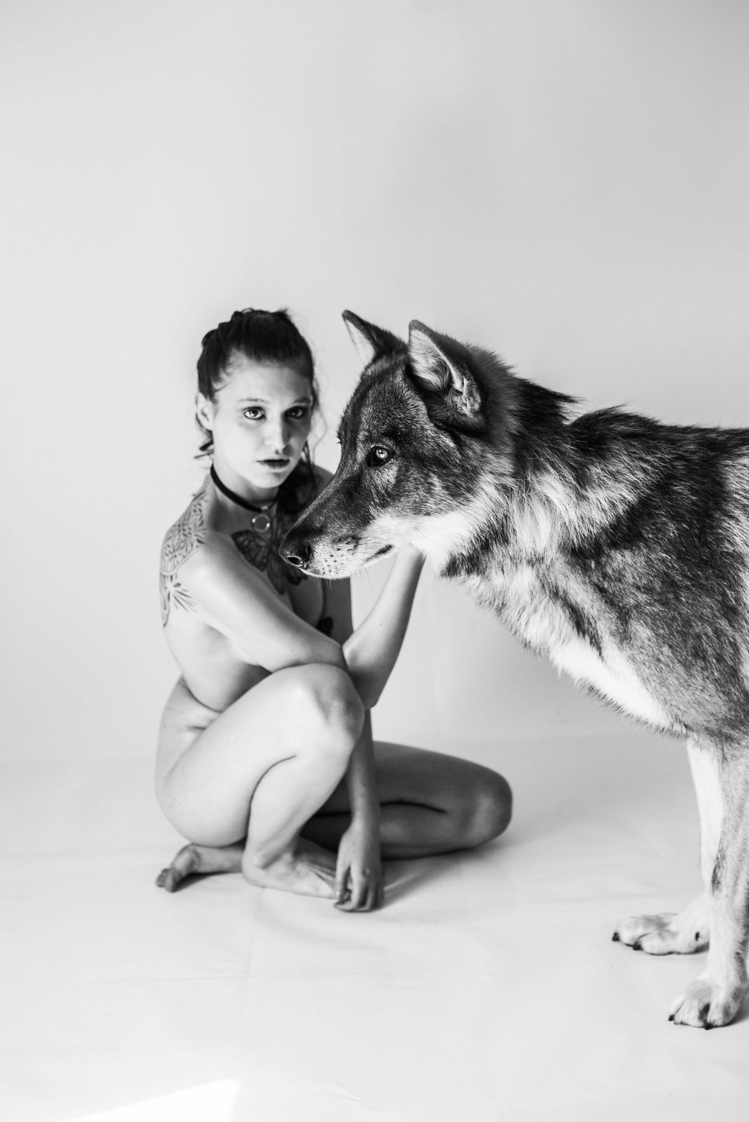 Studio photography series showing choreographed poses between person and wolf.