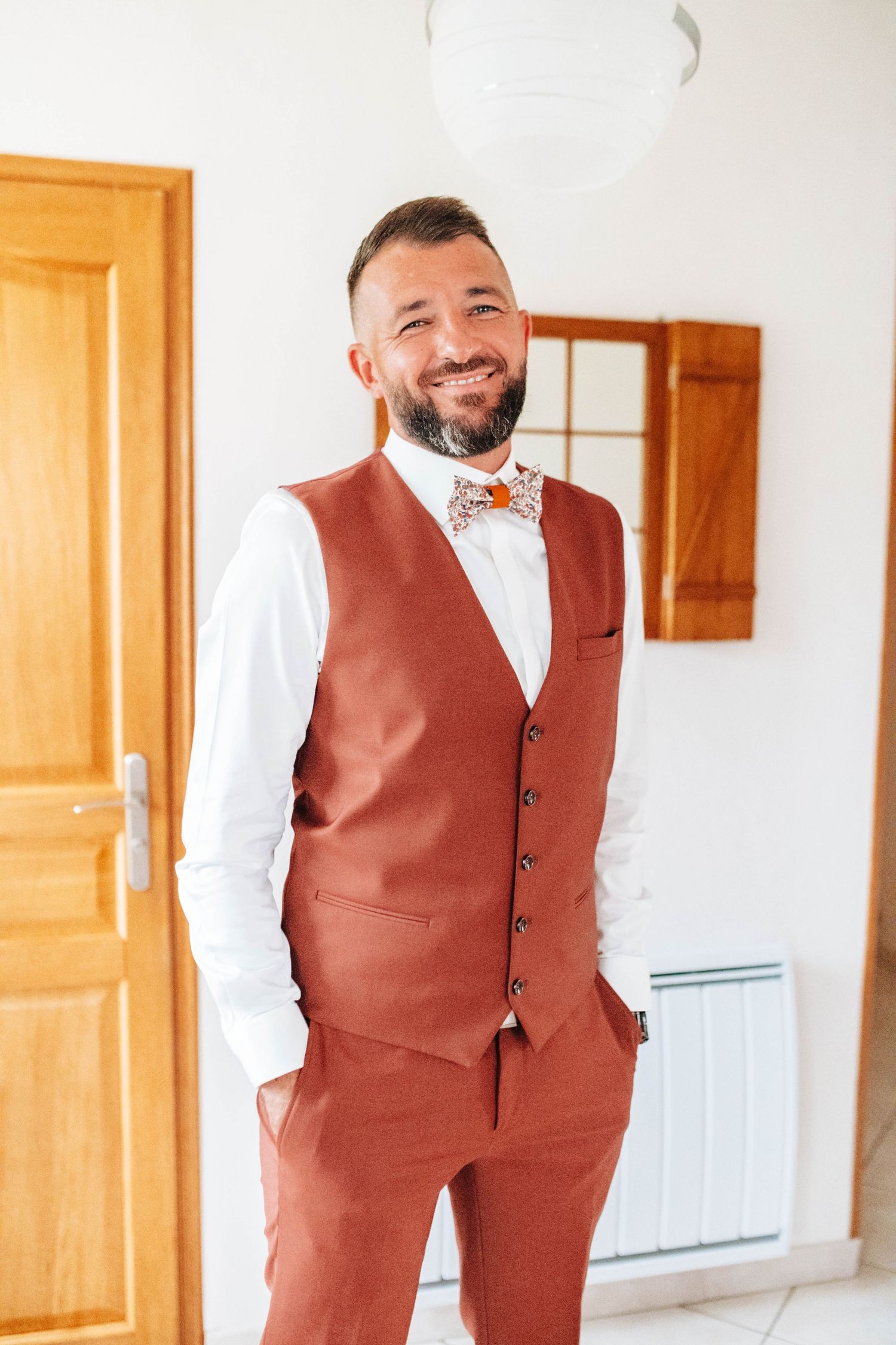 Person in a brown vest and white shirt smiling in a bright indoor setting.