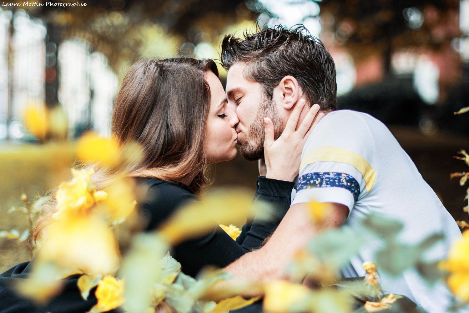 Romantic couple sharing tender moments in a garden with yellow flowers in the background.