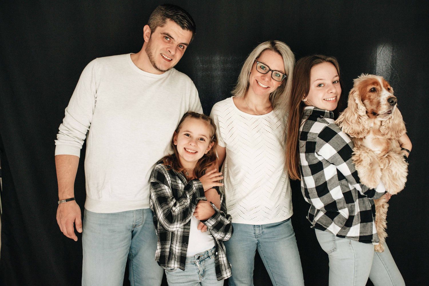 Casual family photo session against a dark background wearing coordinated black and white outfits.