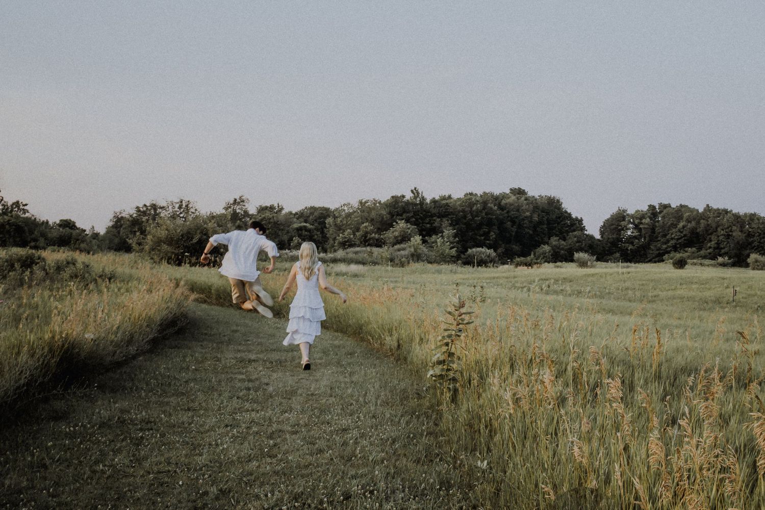 Couple walking through a grassy field during a natural outdoor couples photography session