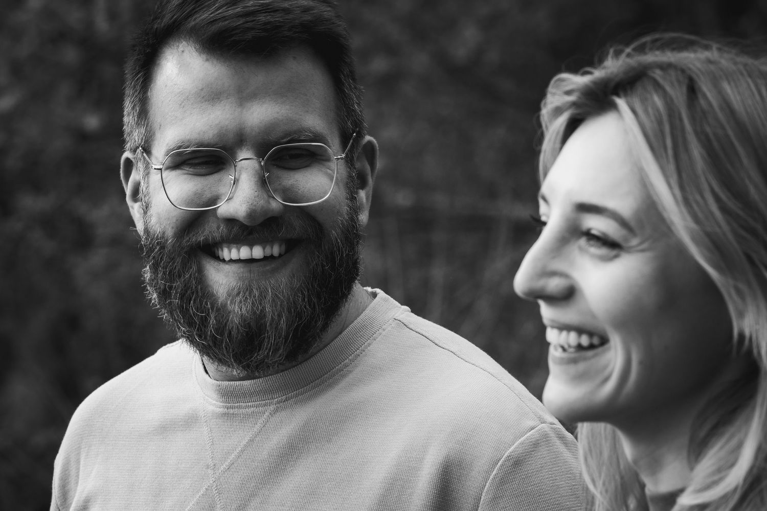 Authentic and romantic portrait of a young couple laughing together during an outdoor photoshoot.