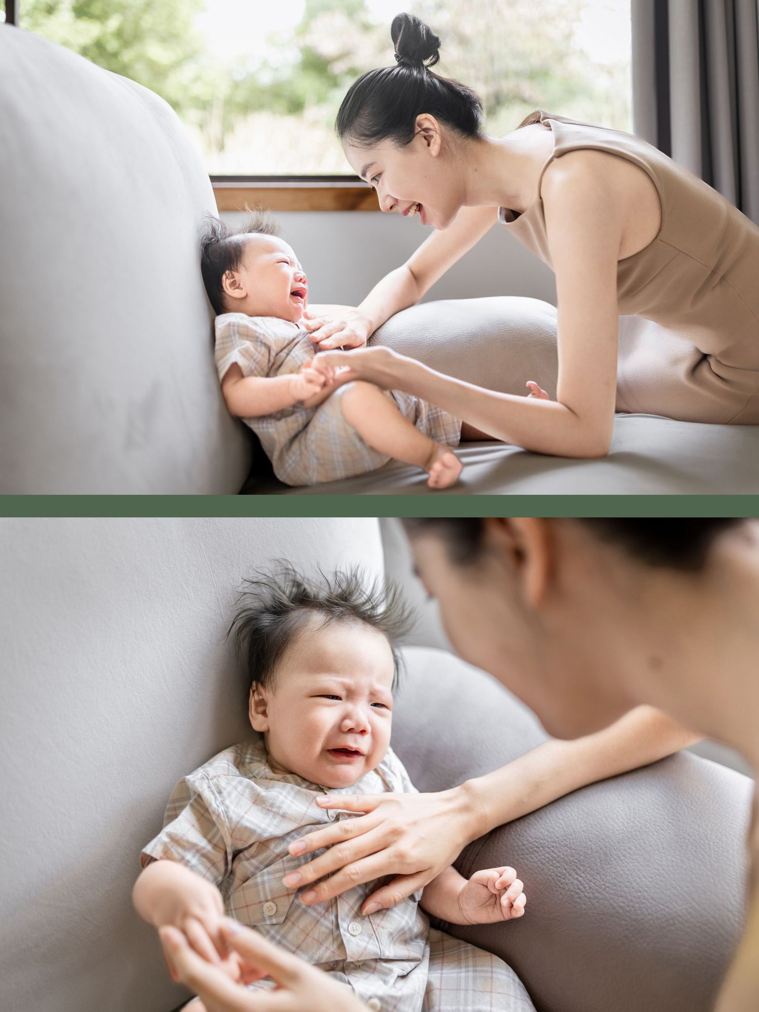 A smiling mother interacts with her crying baby on a gray sofa in a bright room.