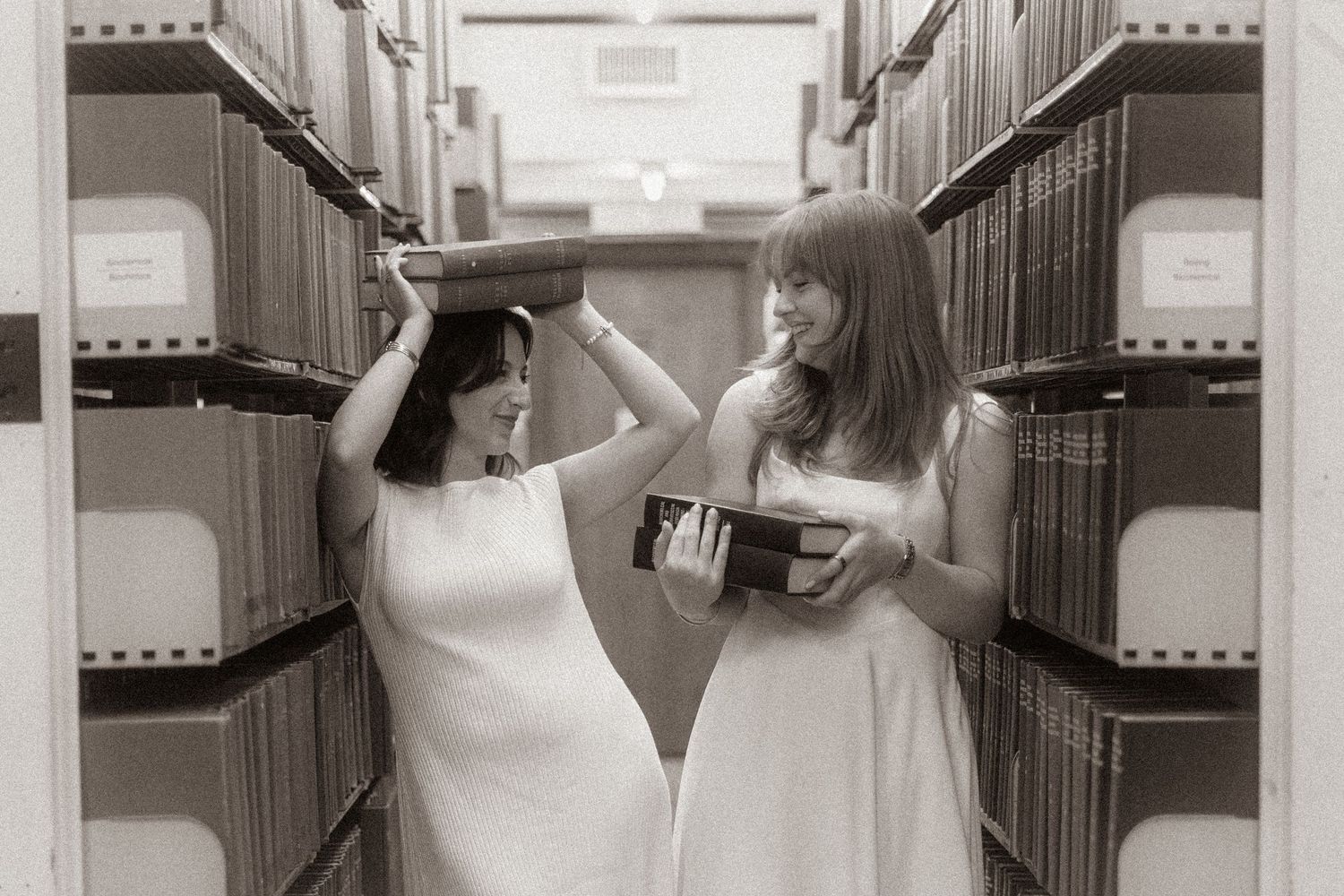 two girls in book stacks playing with books