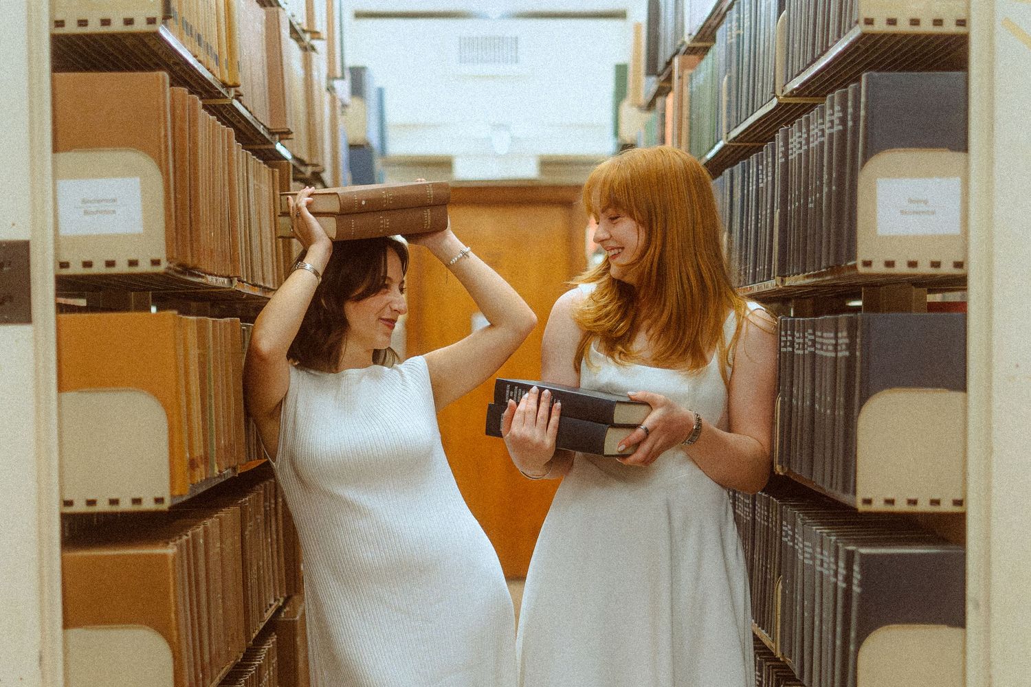 two girls in library messing with books and laughing
