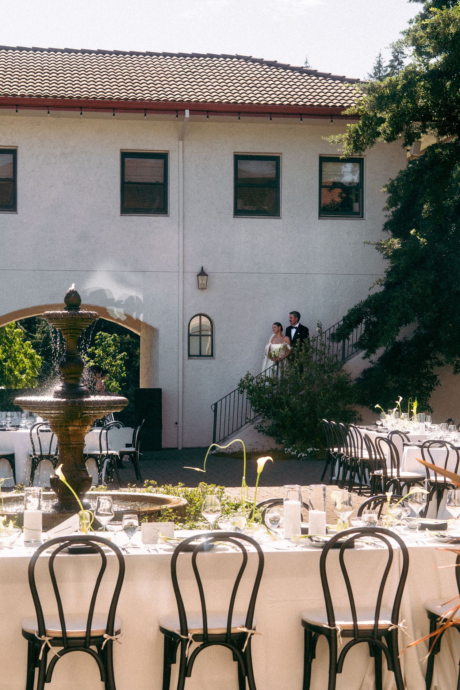 couple posing on steps in background of dining tables