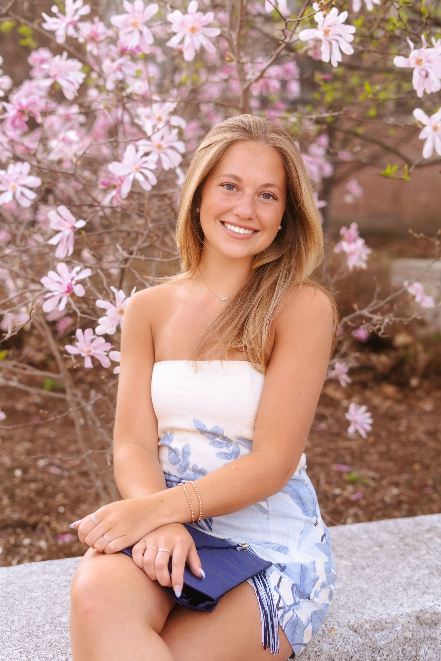 woman sitting down smiling in front of flowers