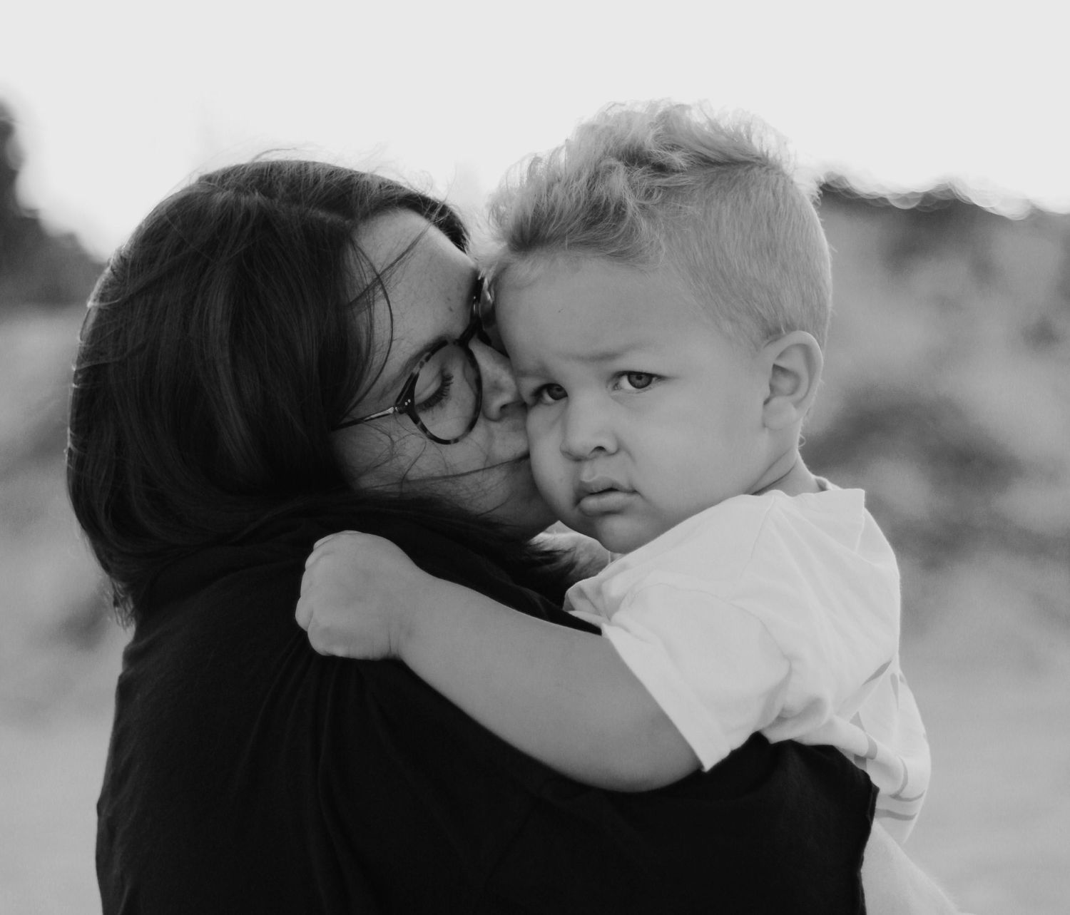 mom giving her pouty son a kiss on the cheek