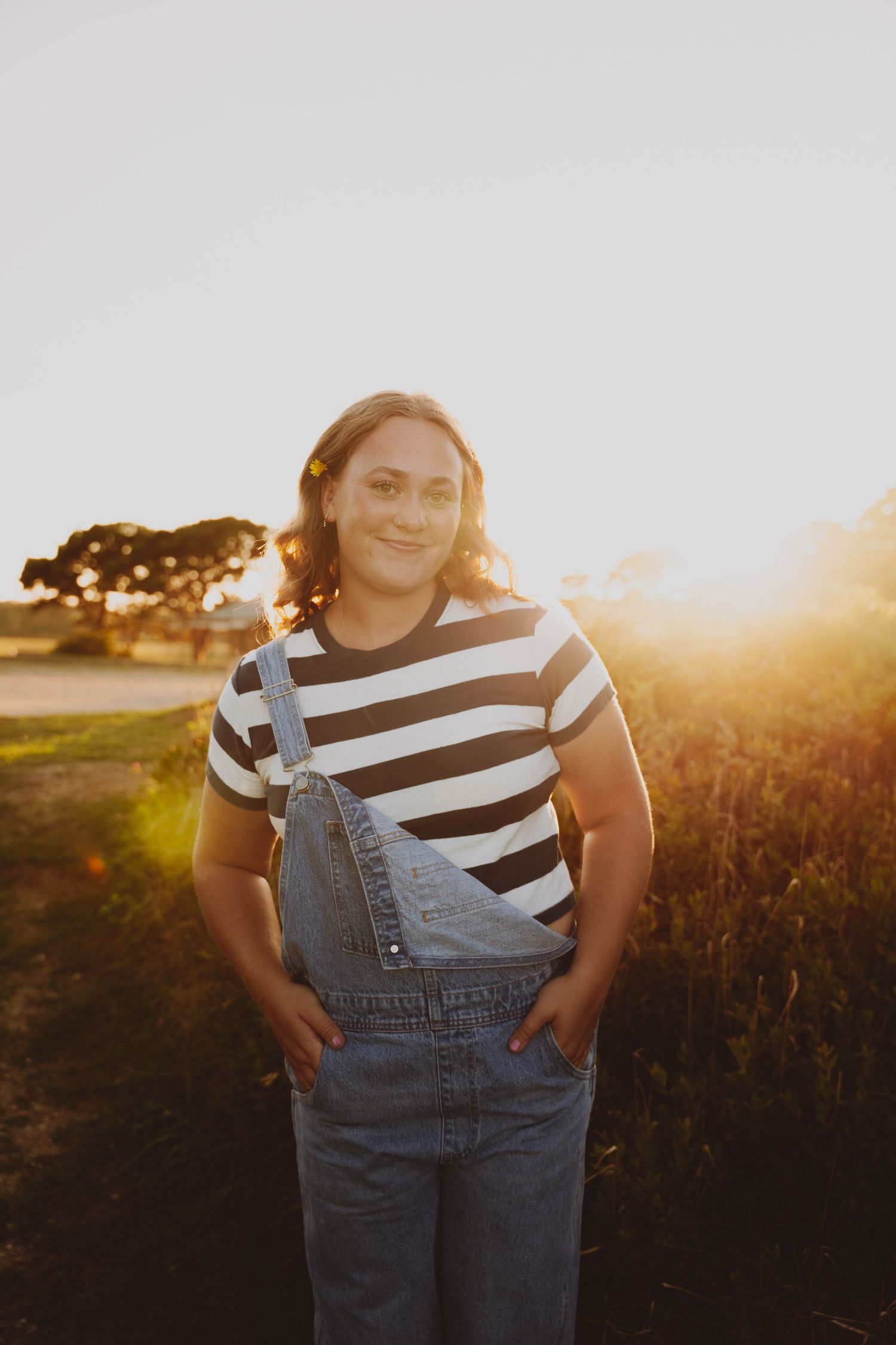 girl smiling at camera in overalls in the sun