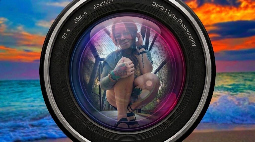 A camera lens reflecting a photographer crouching, set against a vibrant sunset beach backdrop.