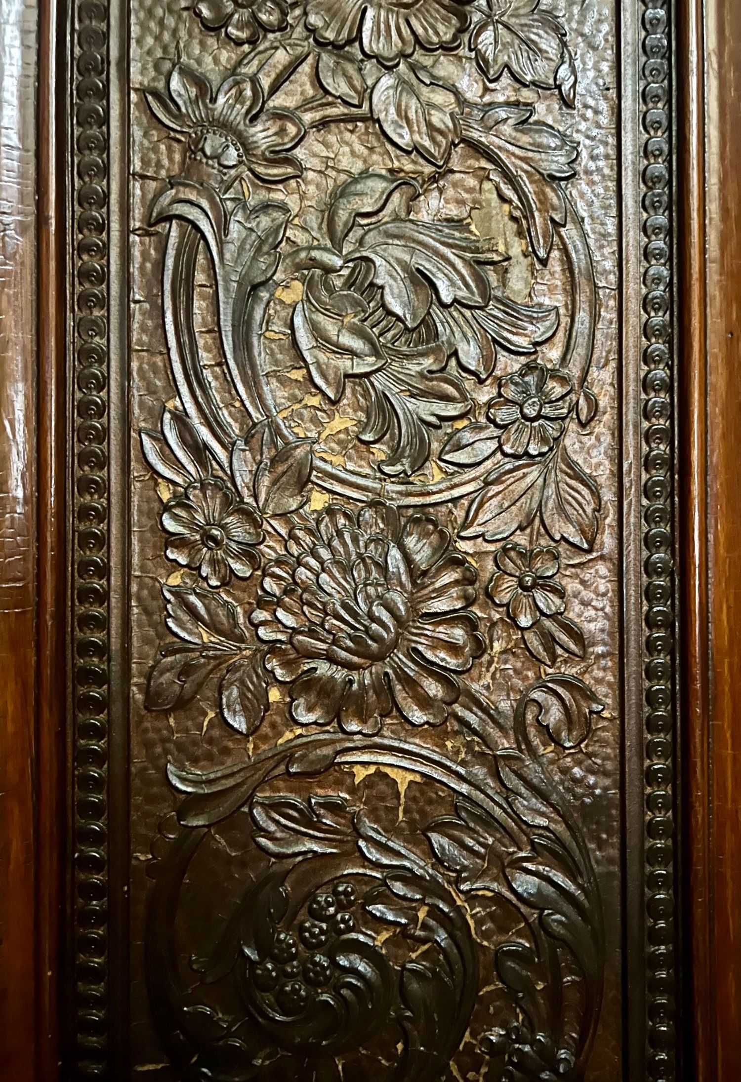 Intricate dark wood carved panel featuring detailed floral and botanical relief designs with chrysanthemums and swirling leaves.