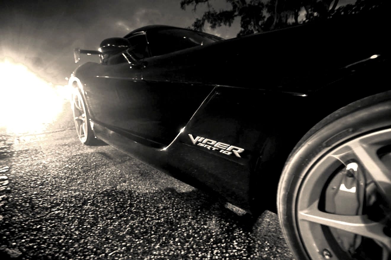 Black Dodge Viper sports car photographed in dramatic black and white lighting at night.